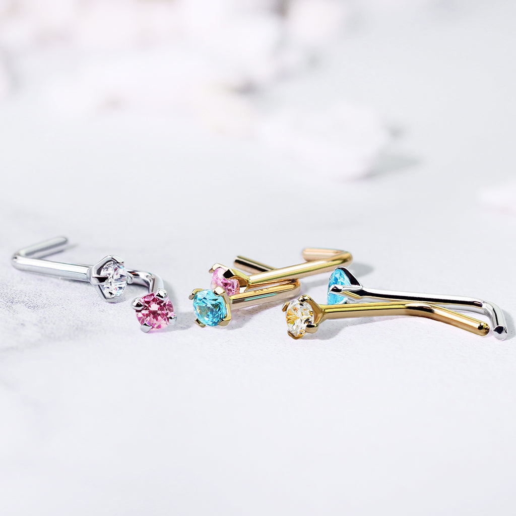 Set van L-vormige neuspiercings met blauwe zirconia in verschillende goudtinten