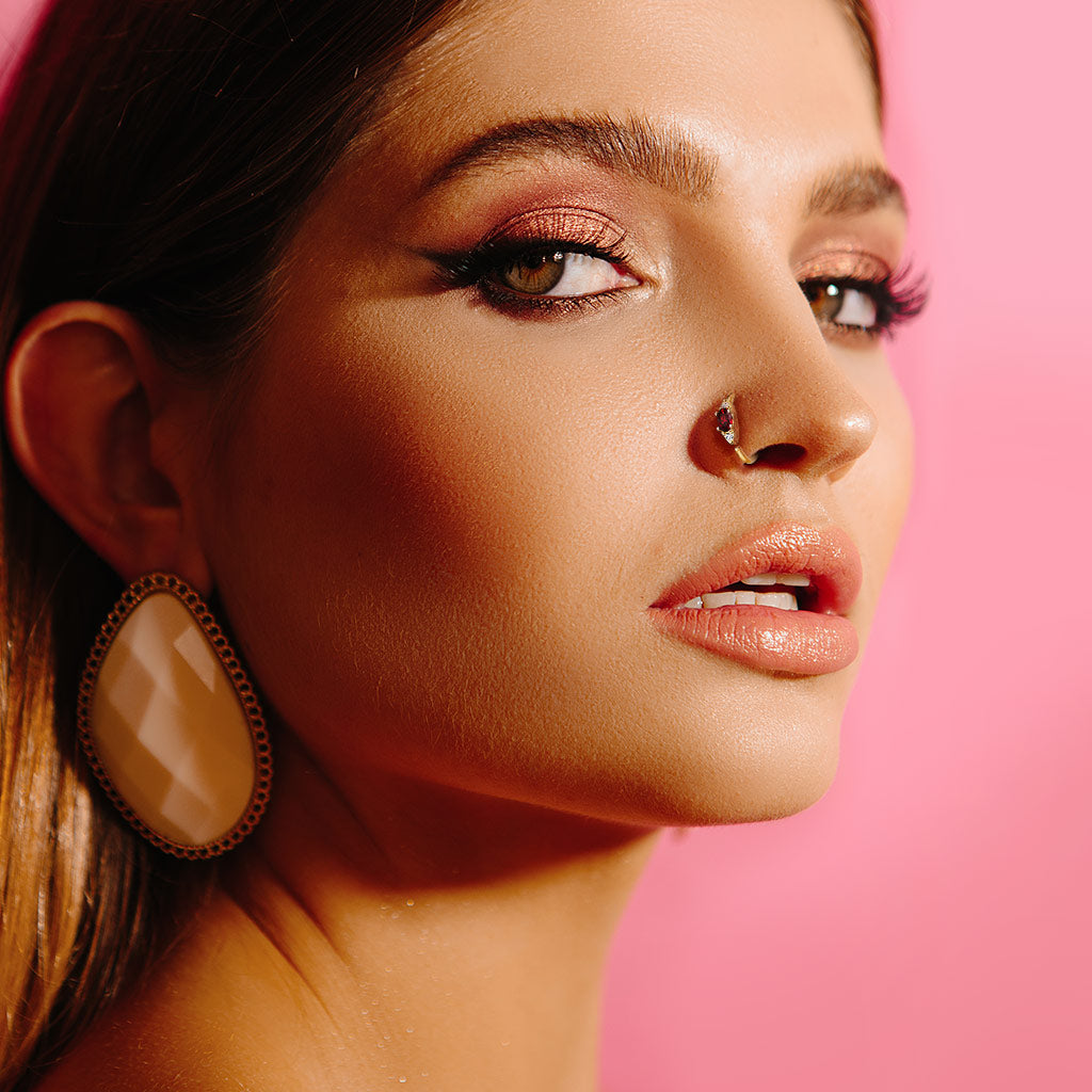 Goudkleurig neusringetje met rode zirconia gedragen in de neus